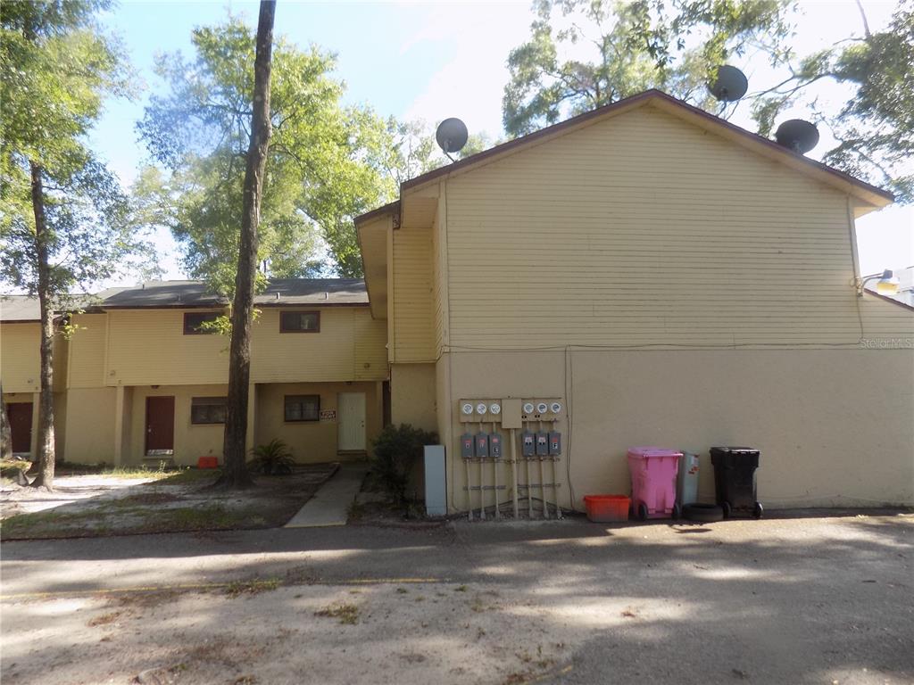 A two-story yellow apartment building exterior with utility meters and trash bins in front — 1110 SW 62 TERRACE UNIT A,B,C,D,E and F, GAINESVILLE, FL
