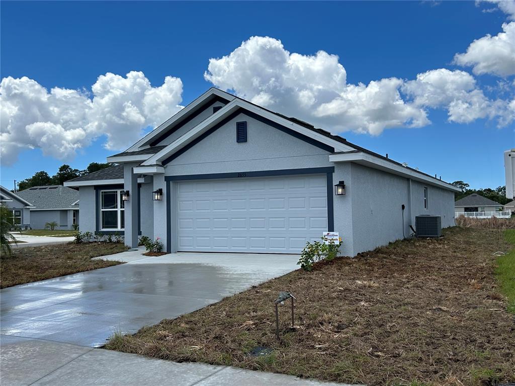 A single-story house with a white garage door, gray stucco walls, and a concrete driveway — 2655 AVERLAND LOOP, NORTH PORT, FL