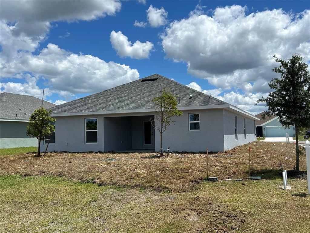 The rear exterior of a single-story gray stucco house with a hip roof and yard — 2655 AVERLAND LOOP, NORTH PORT, FL