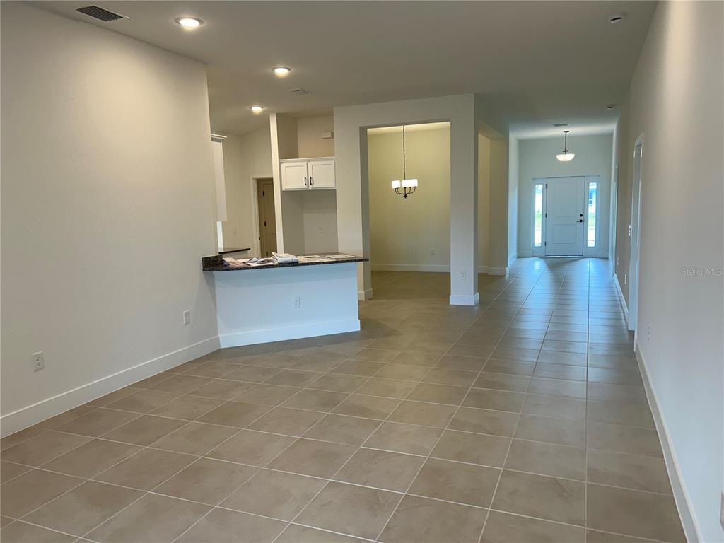 An open-concept interior features tiled floors, a kitchen island, and a view toward the entryway — 2655 AVERLAND LOOP, NORTH PORT, FL