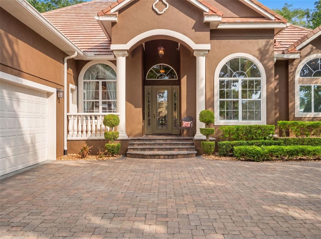 A brown house exterior features a paved driveway, arched windows, and a covered front entrance — 9223 HIDDEN BAY LANE, ORLANDO, FL