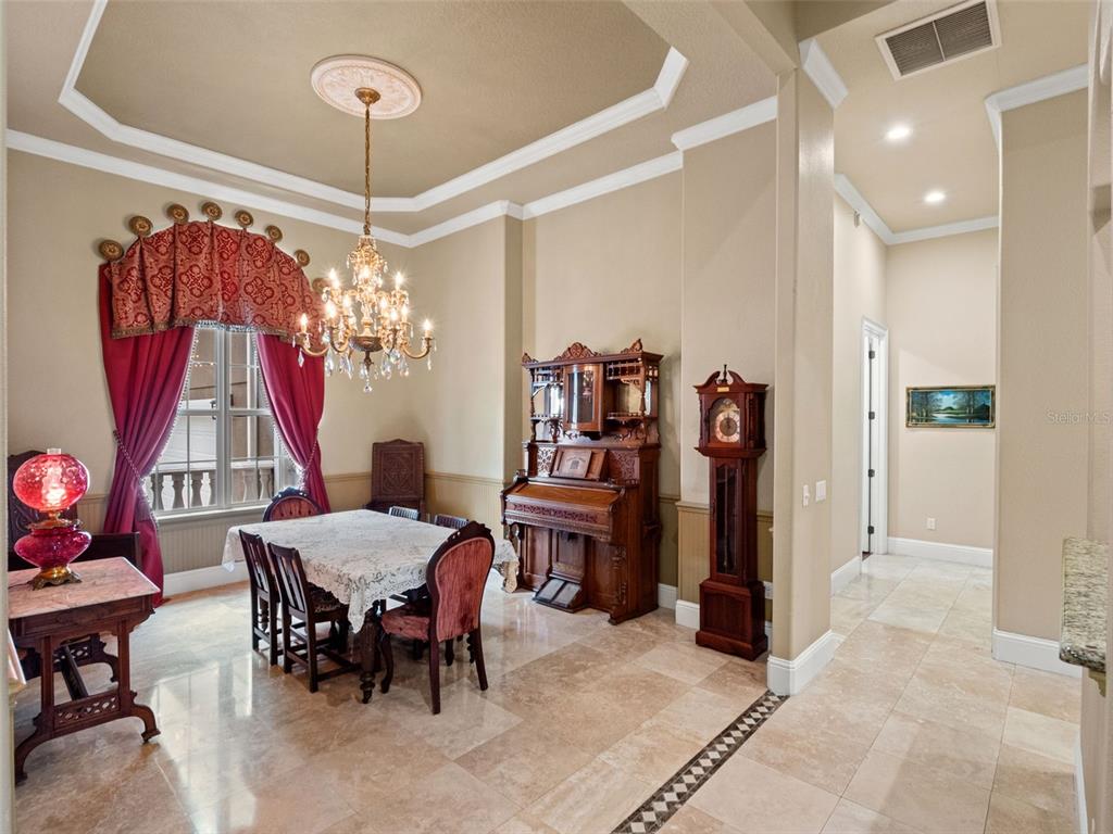 A formal dining room features a chandelier, a piano, a grandfather clock, and tile flooring — 9223 HIDDEN BAY LANE, ORLANDO, FL