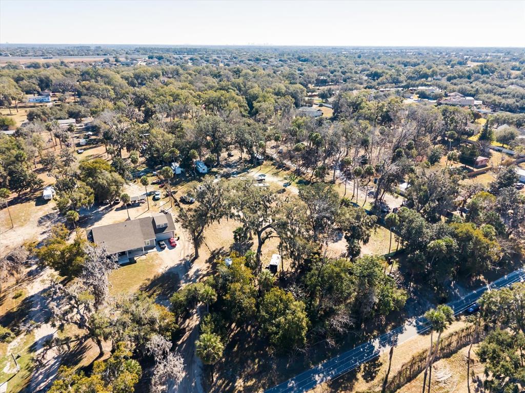 An aerial view shows a house, several parked vehicles, and trailers on a wooded lot — WALKER ROAD, APOPKA, FL
