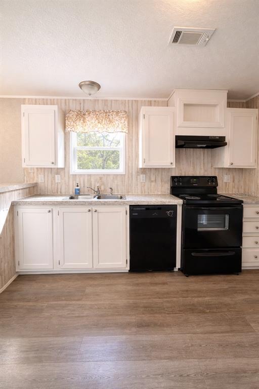 A kitchen with white cabinets, black appliances, laminate countertops, and wood-look flooring — 932 SE 40TH PLACE, MELROSE, FL