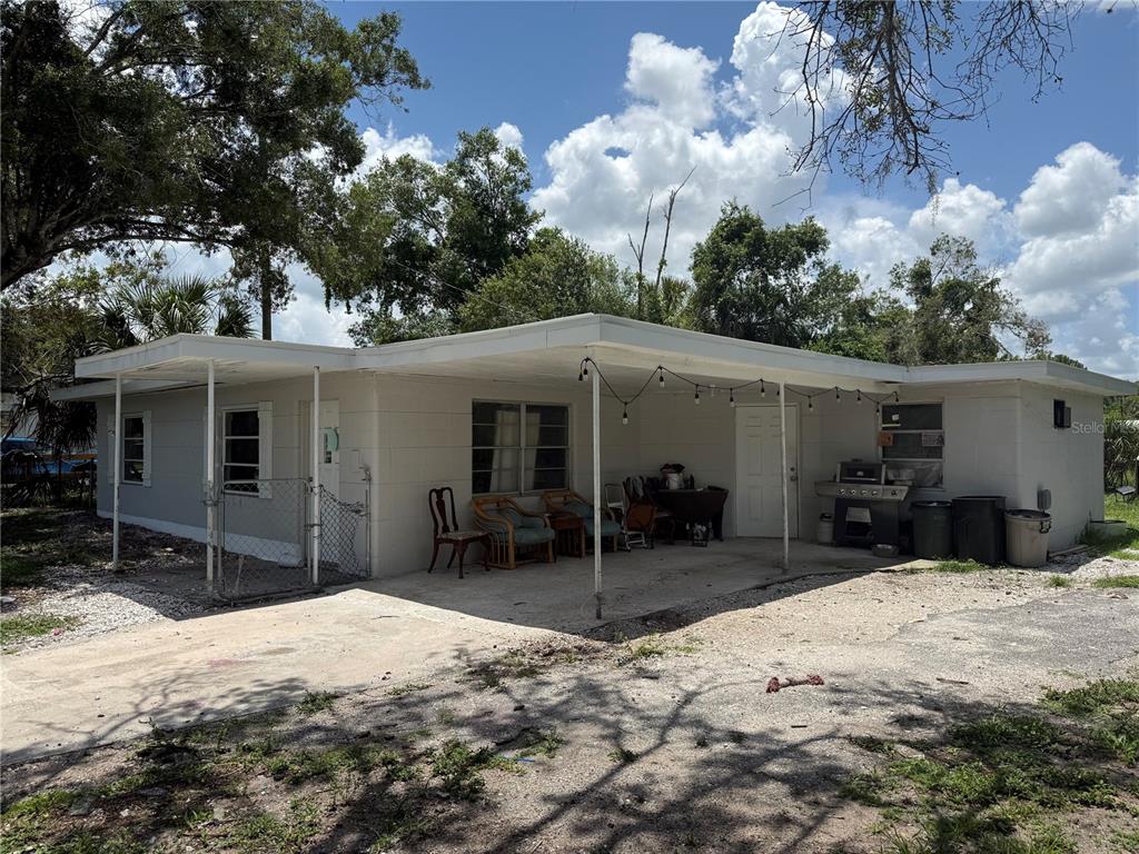 A single-story white house features a large covered patio with string lights and outdoor seating — 408 E MAPLE STREET, ARCADIA, FL