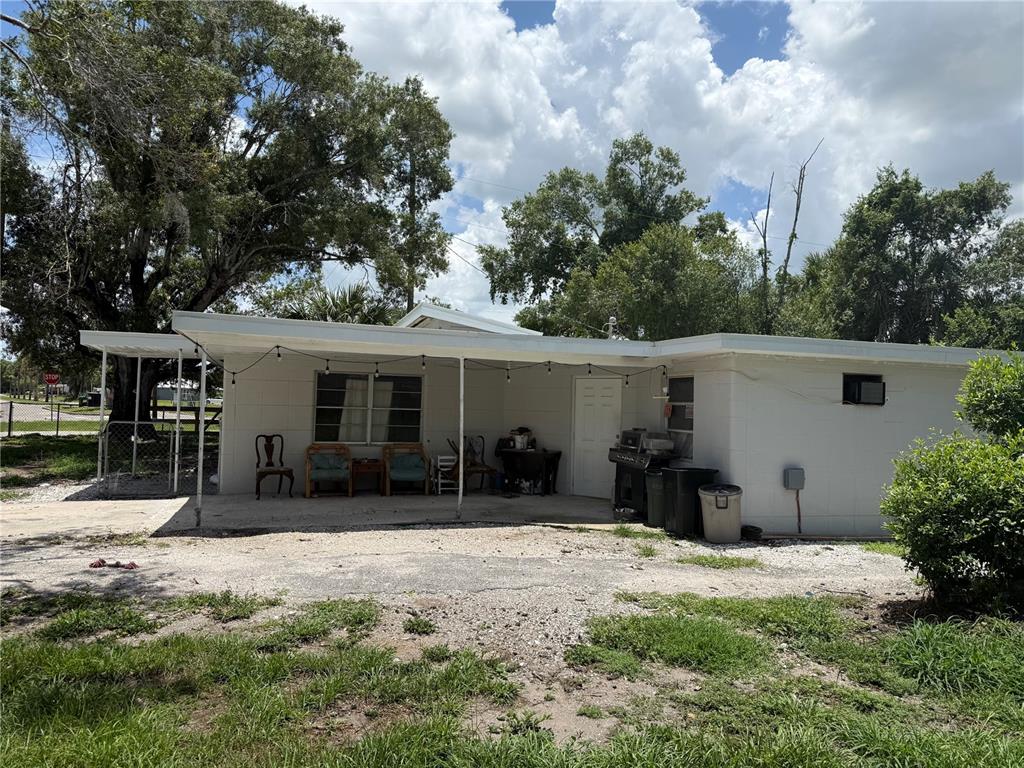 A white concrete block house features a covered patio with string lights and outdoor furniture — 408 E MAPLE STREET, ARCADIA, FL