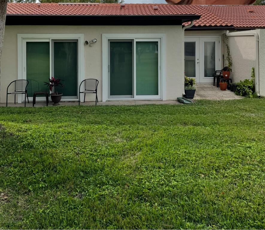 A backyard view of a house with two sliding glass doors and a patio area — 11414 STANSBERRY DRIVE, PORT RICHEY, FL