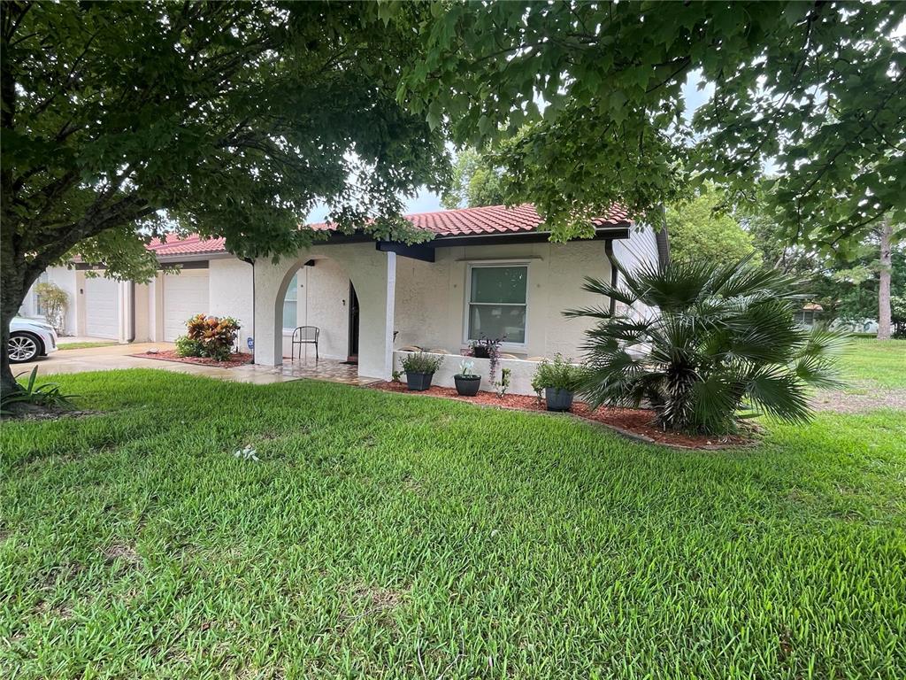 A single-story house with a white stucco exterior, red tile roof, and a front lawn — 11414 STANSBERRY DRIVE, PORT RICHEY, FL