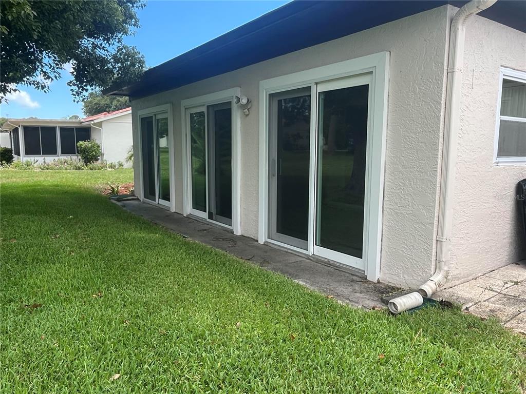 The exterior of a house features two sliding glass doors and a white stucco wall — 11414 STANSBERRY DRIVE, PORT RICHEY, FL