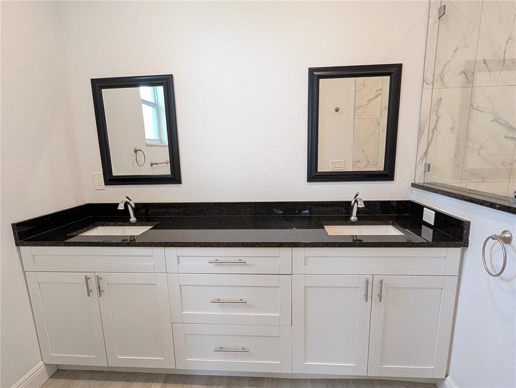 A bathroom vanity with white cabinets, a black granite countertop, and two rectangular sinks — 1643 JEANNIN DRIVE, NORTH PORT, FL