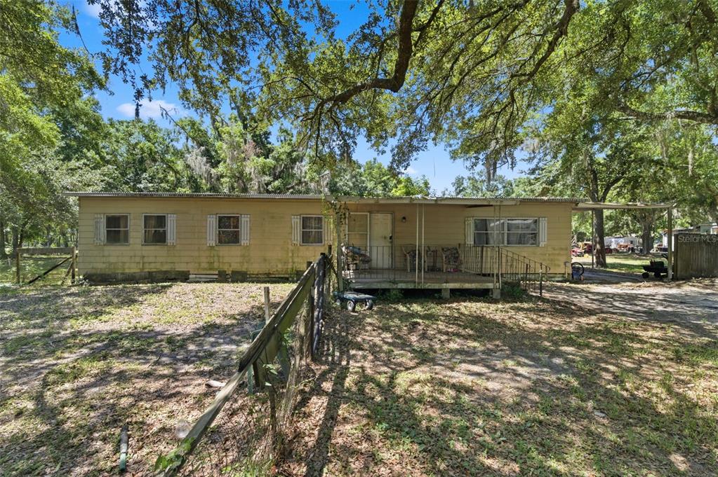 A single-story mobile home with a covered front porch sits on a wooded lot — 17214 CHINABERRY ROAD, LUTZ, FL