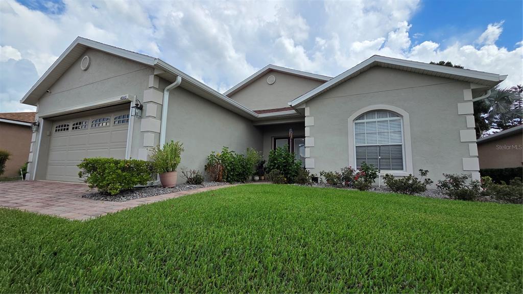 A single-story house with a beige stucco exterior, a two-car garage, and a front lawn — 4063 BIRKDALE DRIVE, LAKE WALES, FL