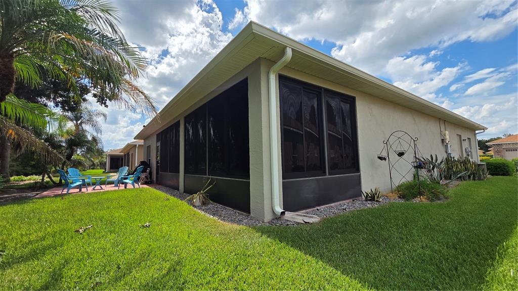 A beige house exterior features a screened-in porch, a white downspout, and a grassy yard — 4063 BIRKDALE DRIVE, LAKE WALES, FL