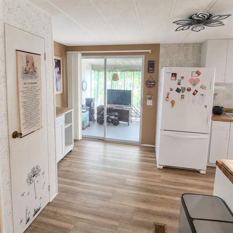 A kitchen with wood-look flooring, white cabinets, a white refrigerator, and sliding glass doors — 4122 CARDOON DRIVE, NEW PORT RICHEY, FL