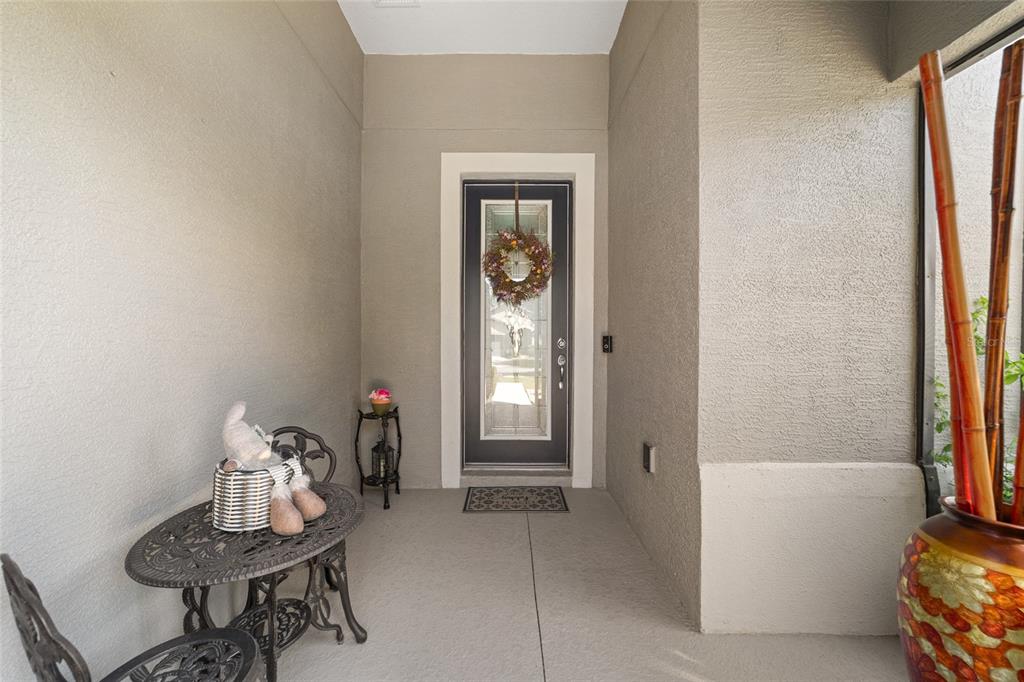 A covered entryway features a dark front door with a glass insert and a small bistro set — 9300 SW 70TH LOOP, OCALA, FL