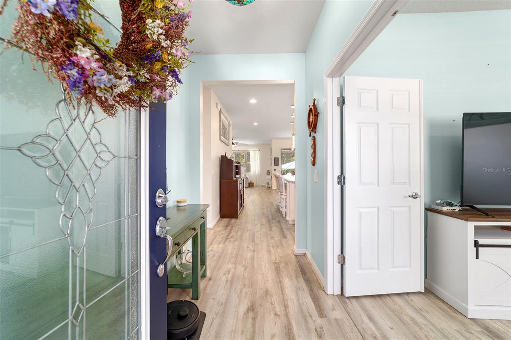 An entryway with light blue walls, wood-look flooring, and a view into the living area — 9300 SW 70TH LOOP, OCALA, FL