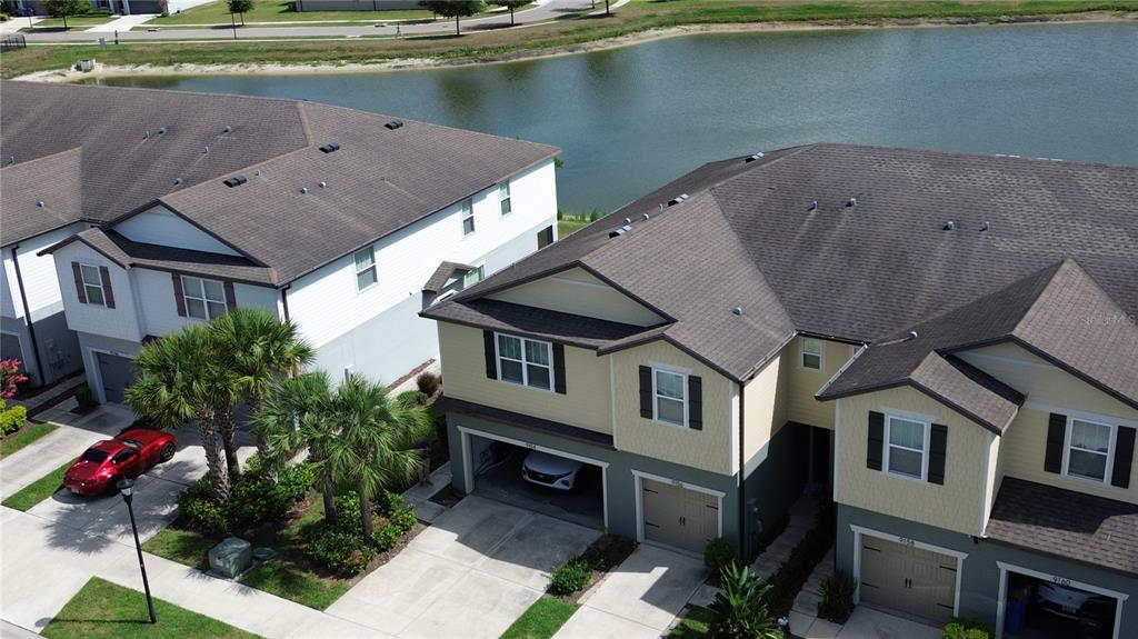 An aerial view shows two multi-story townhomes with attached garages and a nearby pond — 9154 HILLCROFT DRIVE, RIVERVIEW, FL