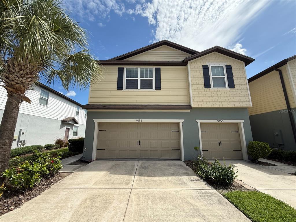 A two-story duplex with tan siding, a gray lower level, and two attached garages — 9154 HILLCROFT DRIVE, RIVERVIEW, FL