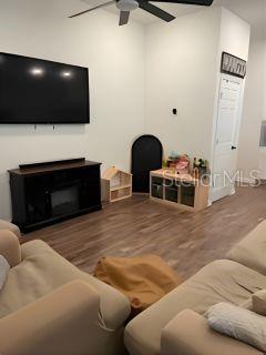 A living room with wood-look flooring, a wall-mounted television, and a dark media console — 8083 GUILD WAY, JACKSONVILLE, FL