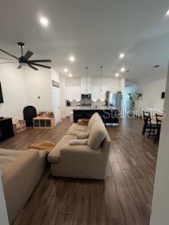 An open-concept living room and kitchen with light-colored furniture and wood-look tile flooring — 8083 GUILD WAY, JACKSONVILLE, FL