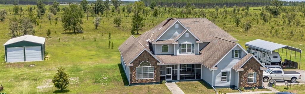 An aerial view of a two-story house with a stone facade, screened porch, and detached garage — 732 SE SIDE WHEEL TRAIL, LEE, FL