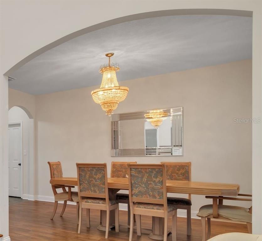 A dining room features a crystal chandelier, a rectangular mirror, and a wooden dining set — 732 SE SIDE WHEEL TRAIL, LEE, FL