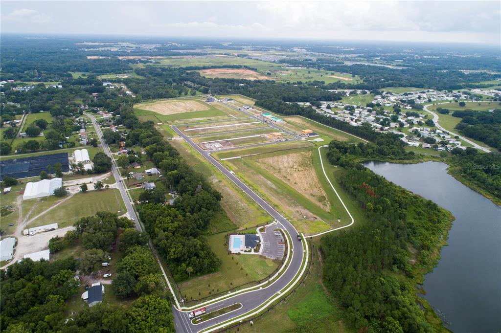 An aerial view shows a new residential development under construction next to a large lake — 2957 SWEETGRASS LANE, ZELLWOOD, FL