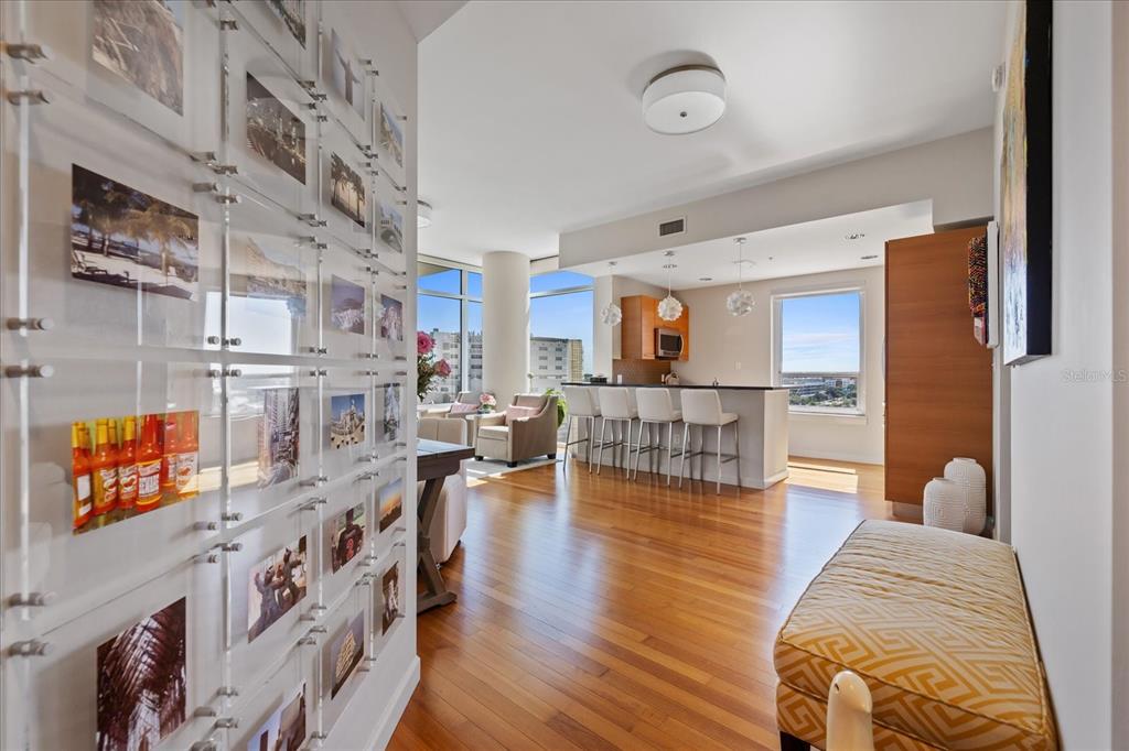 An open-concept living area features hardwood floors, a kitchen island with bar seating, and a photo-covered wall — 400 4TH AVENUE S UNIT 1004, ST PETERSBURG, FL