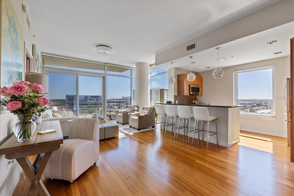 An open-concept living and kitchen area with hardwood floors, floor-to-ceiling windows, and a breakfast bar — 400 4TH AVENUE S UNIT 1004, ST PETERSBURG, FL
