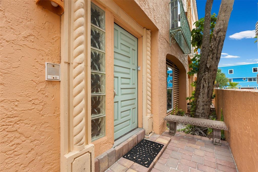 A light green front door with glass block sidelights sits on a paved patio area — 306 BEACH ROAD UNIT 306, SARASOTA, FL