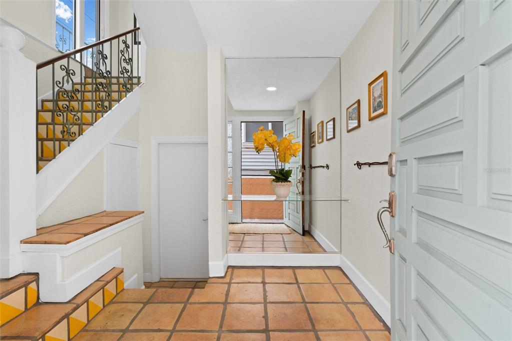 An entryway features terracotta tile flooring, a staircase with yellow accents, and a mirrored wall — 306 BEACH ROAD UNIT 306, SARASOTA, FL