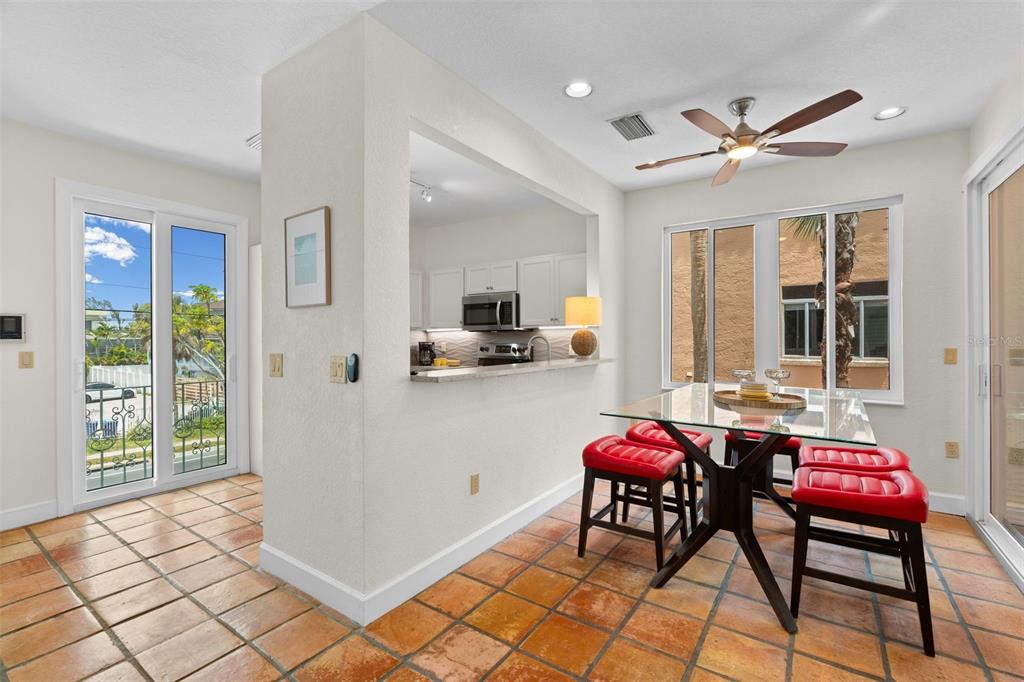 A dining area with a glass table, red stools, and a pass-through to the kitchen — 306 BEACH ROAD UNIT 306, SARASOTA, FL