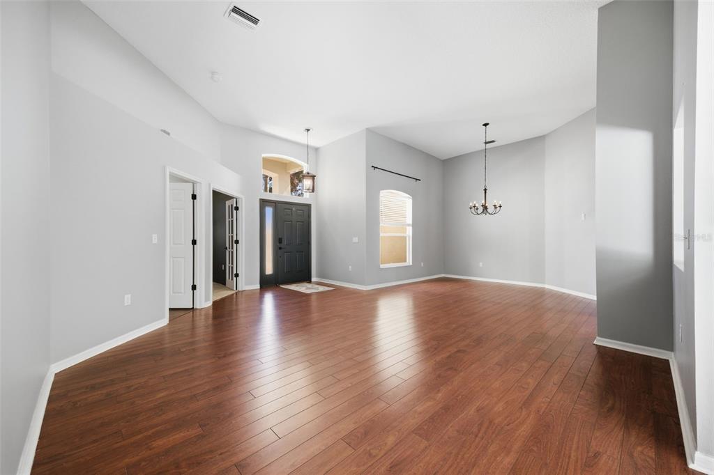 A spacious living room features light gray walls, high ceilings, and dark wood flooring — 3209 PARTRIDGE POINT TRAIL, VALRICO, FL