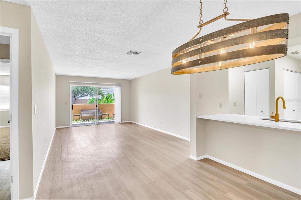An open living area features light wood flooring, a breakfast bar, and a sliding glass door — 612 KENWICK CIRCLE UNIT 103, CASSELBERRY, FL