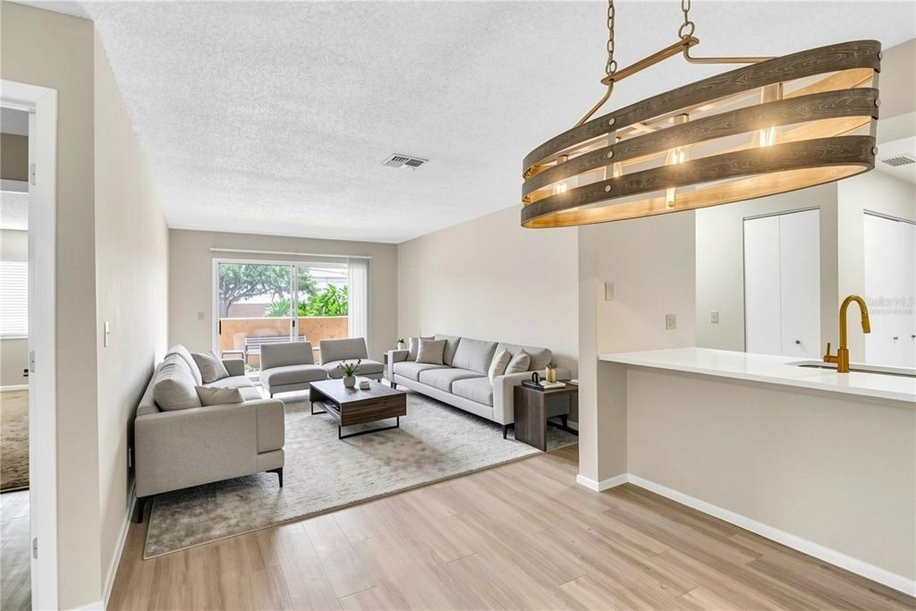 A living room features light wood flooring, a gray sofa set, and a rustic chandelier — 612 KENWICK CIRCLE UNIT 103, CASSELBERRY, FL