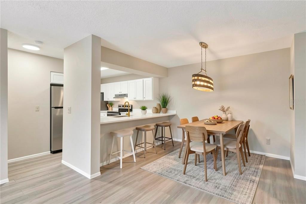 A dining area with a wooden table and chairs sits adjacent to a kitchen counter — 612 KENWICK CIRCLE UNIT 103, CASSELBERRY, FL