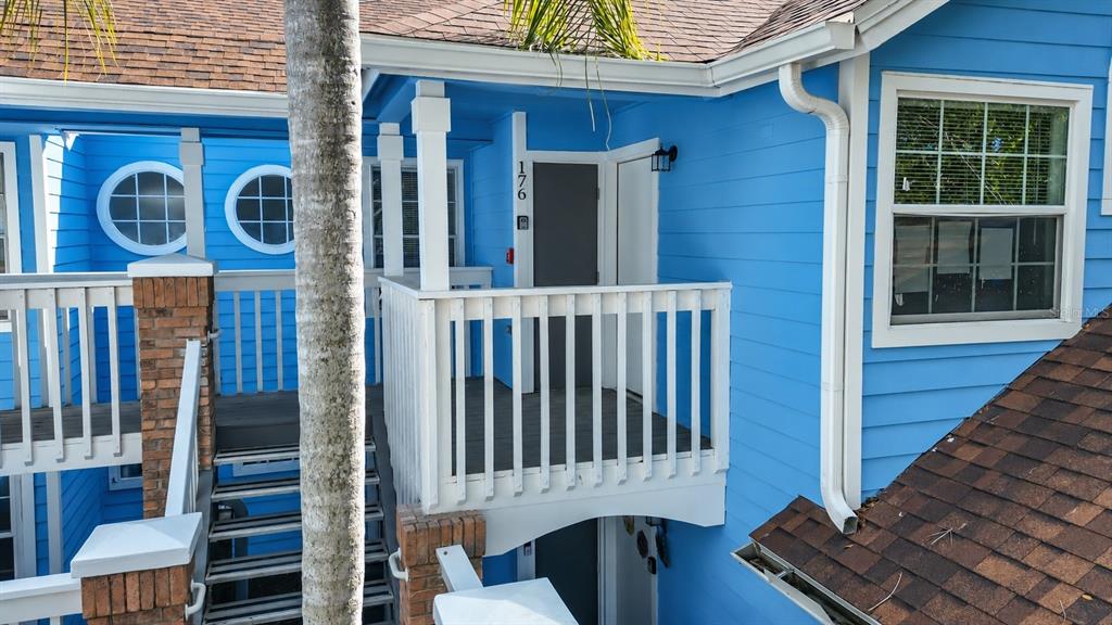 A blue exterior building features a wooden staircase leading to an elevated balcony entrance — 2717 N POINCIANA BOULEVARD UNIT 176, KISSIMMEE, FL