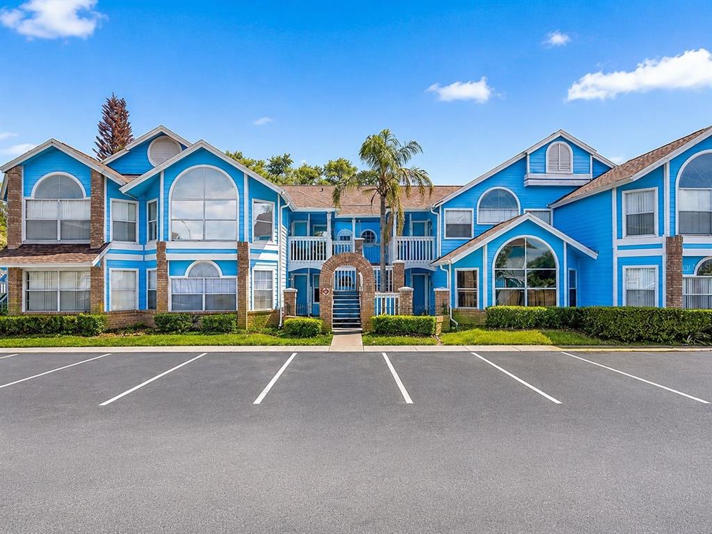 A two-story blue apartment building with arched windows and a central brick entryway — 2717 N POINCIANA BOULEVARD UNIT 176, KISSIMMEE, FL