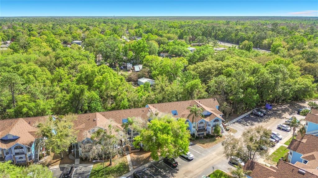 An aerial view shows multi-story apartment buildings surrounded by dense trees and parking lots — 2717 N POINCIANA BOULEVARD UNIT 176, KISSIMMEE, FL