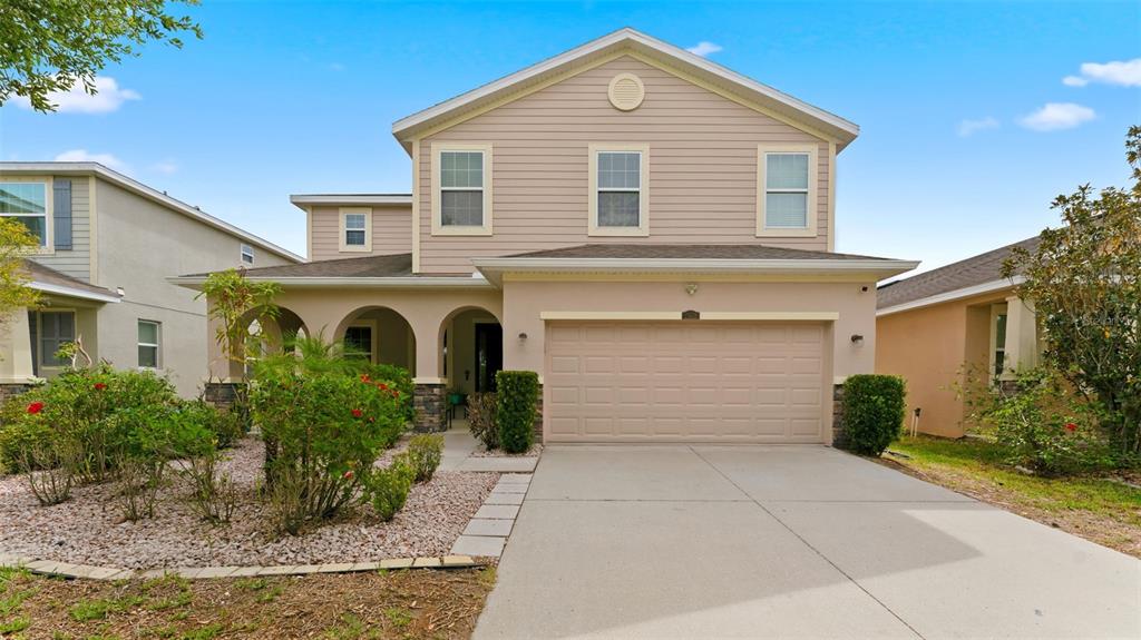 A two-story suburban house features a beige facade, a two-car garage, and a front porch — 11620 WARREN OAKS PL, RIVERVIEW, FL