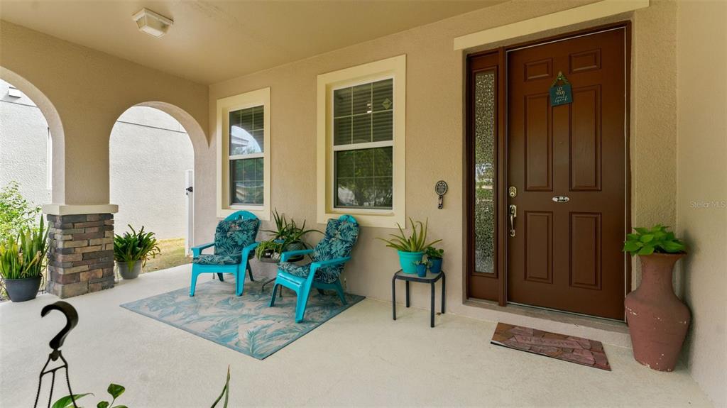 A covered front porch features two blue chairs, potted plants, and a brown front door — 11620 WARREN OAKS PL, RIVERVIEW, FL