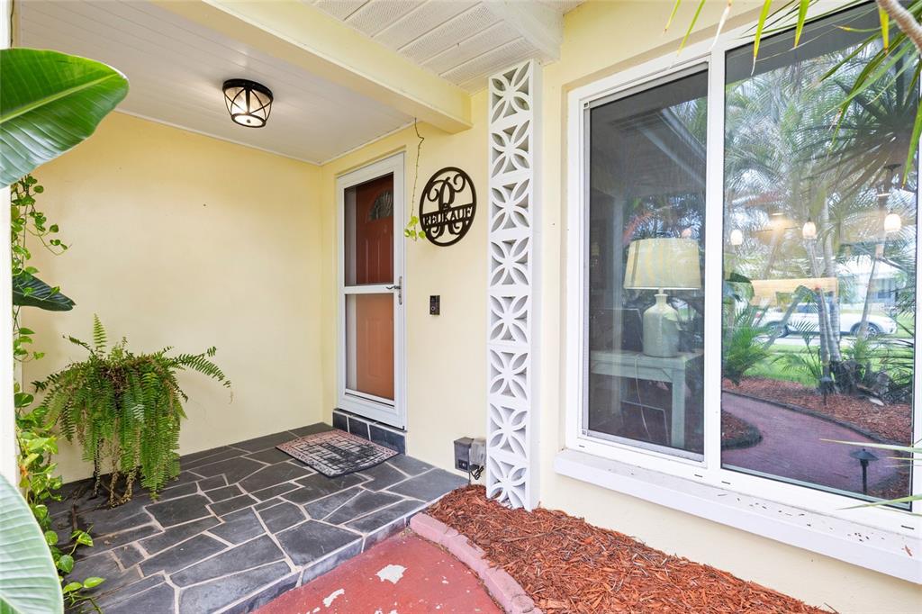 A covered entryway features a stone floor, a decorative screen block column, and a front door — 1070 MCCARTY STREET, DUNEDIN, FL