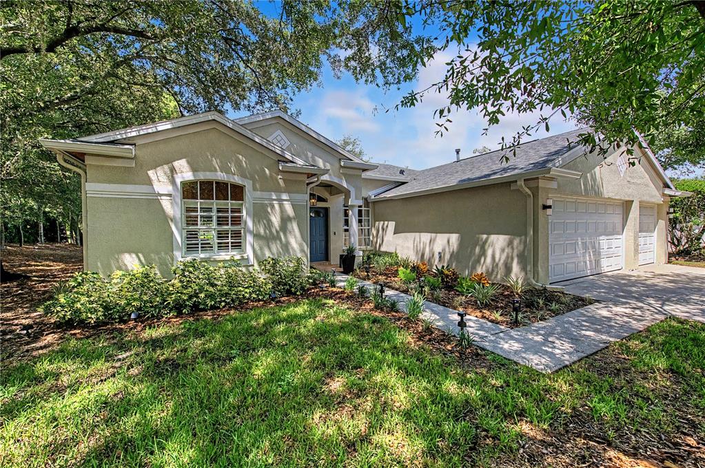A single-story house with a beige stucco exterior, a blue front door, and a garage — 9402 HUNTERS POND DRIVE, TAMPA, FL
