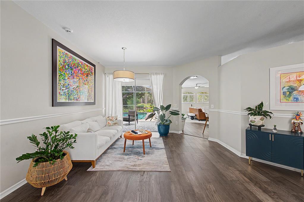 A living room with white walls, wood floors, a sofa, and a view of a pool — 9402 HUNTERS POND DRIVE, TAMPA, FL