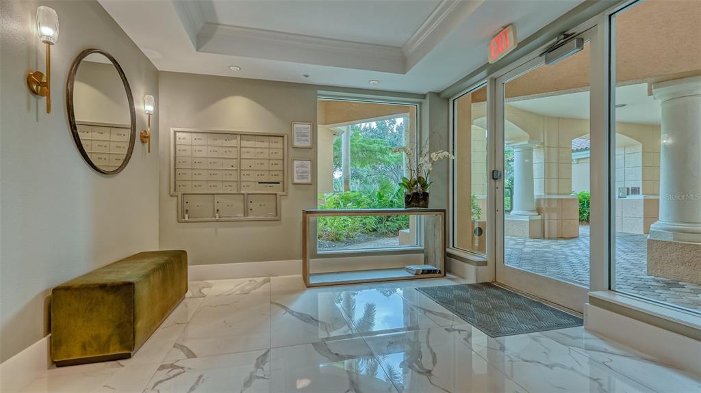 A bright lobby features marble floors, a wall-mounted mailbox unit, a bench, and glass doors — 401 N POINT ROAD UNIT 301, OSPREY, FL