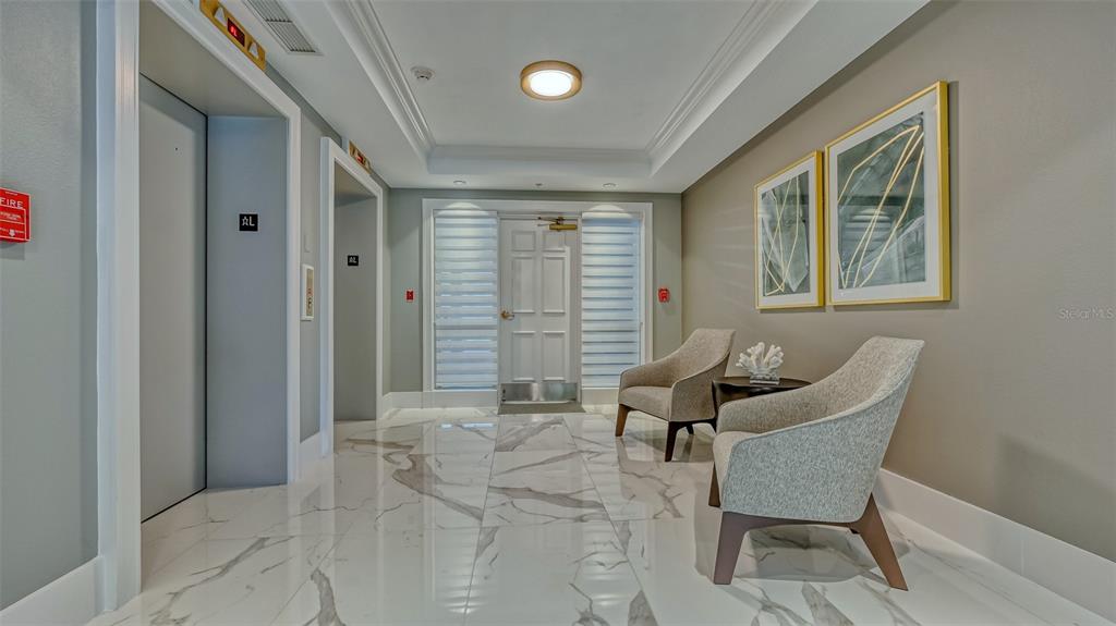 A modern building lobby features marble floors, two armchairs, and two elevators — 401 N POINT ROAD UNIT 301, OSPREY, FL
