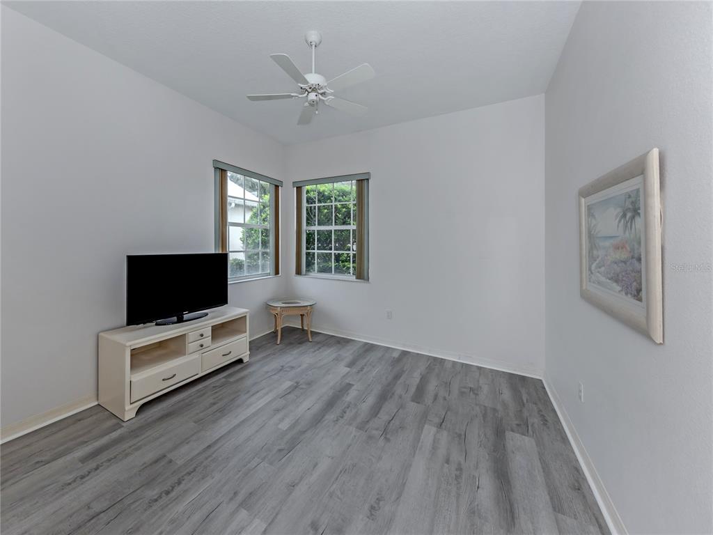 A living room with blue sofas, glass-topped tables, and a sliding door to a patio — 737 POND LILY WAY, VENICE, FL