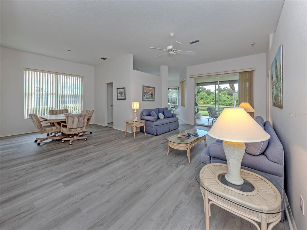 A living room features two blue sofas, glass-topped tables, and a sliding door to a patio — 737 POND LILY WAY, VENICE, FL