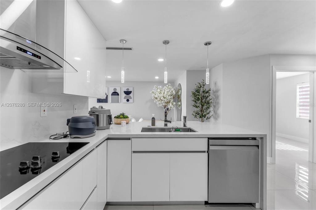 A modern kitchen features white cabinets, stainless steel appliances, and a white quartz island — 1180 NW 124TH PLACE UNIT 208, MIAMI, FL