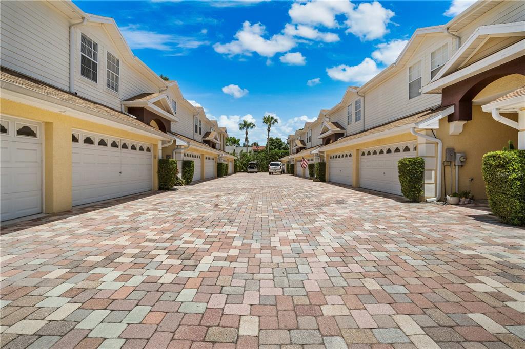 A paved driveway leads between two rows of townhouses with white garage doors — 2974 ESTANCIA PLACE, CLEARWATER, FL